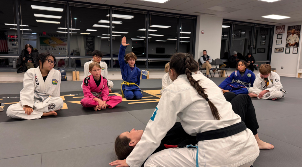 Youth BJJ Class at Pedro Sauer Academy of Self-Defense, Herndon VA - Pedro Sauer Academy - Pedro Sauer Academy Youth Brazilian Jiu-Jitsu gi class at Pedro Sauer Academy of Self-Defense in Herndon, VA, with Coach Nina demonstrating a side-control escape.