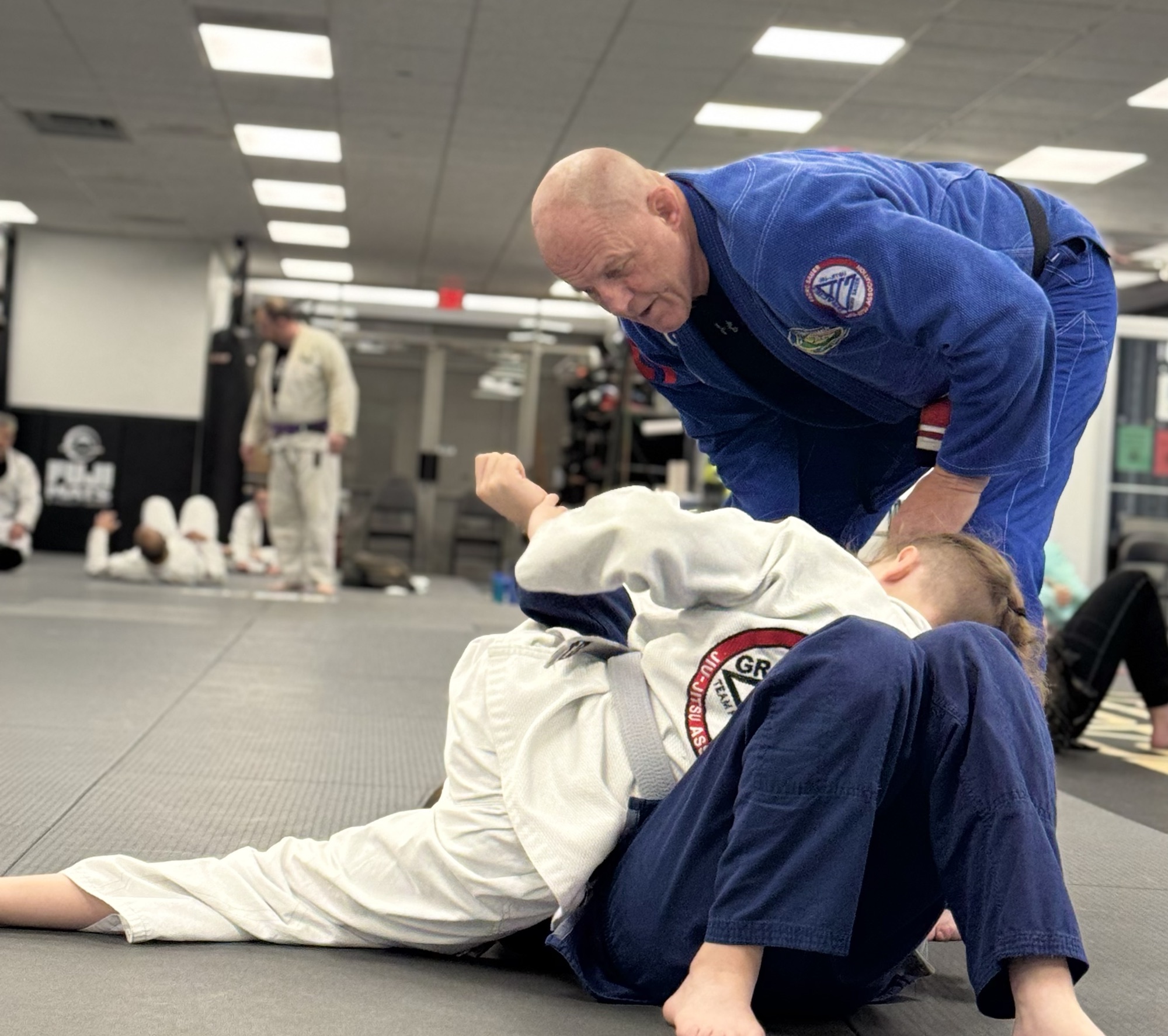 An instructor coaching a Youth Jiu-jitsu student during supervised training at Pedro Sauer Academy