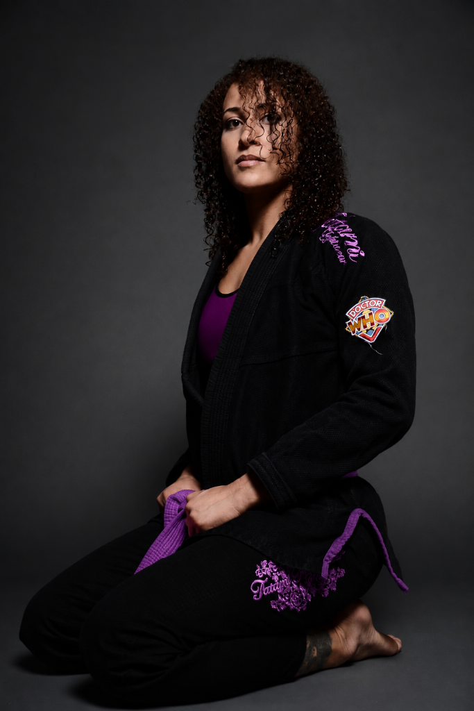 coach-chloe - Pedro Sauer Academy of Self-Defense - Pedro Sauer Academy of Self-Defense Coach Chlóe in a black Brazilian Jiu-jitsu gi holding her purple belt.