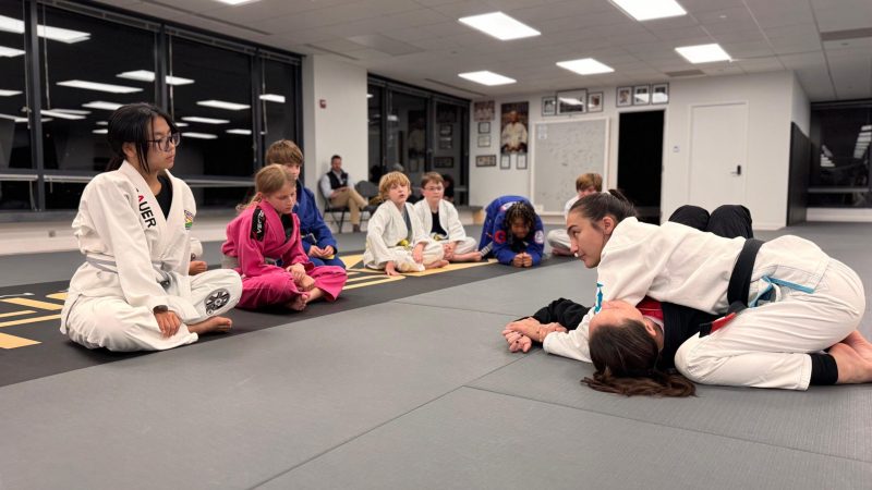 Youth jiu jitsu sport class with children watching a Brazilian Jiu-Jitsu technique demonstration at Pedro Sauer Academy